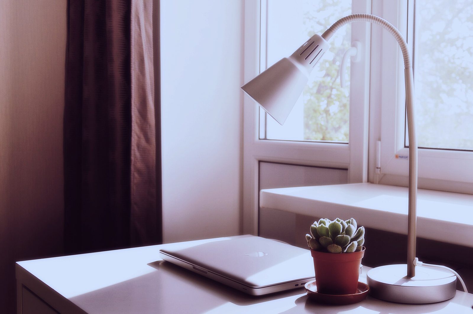 A desk with a laptop and a lamp
